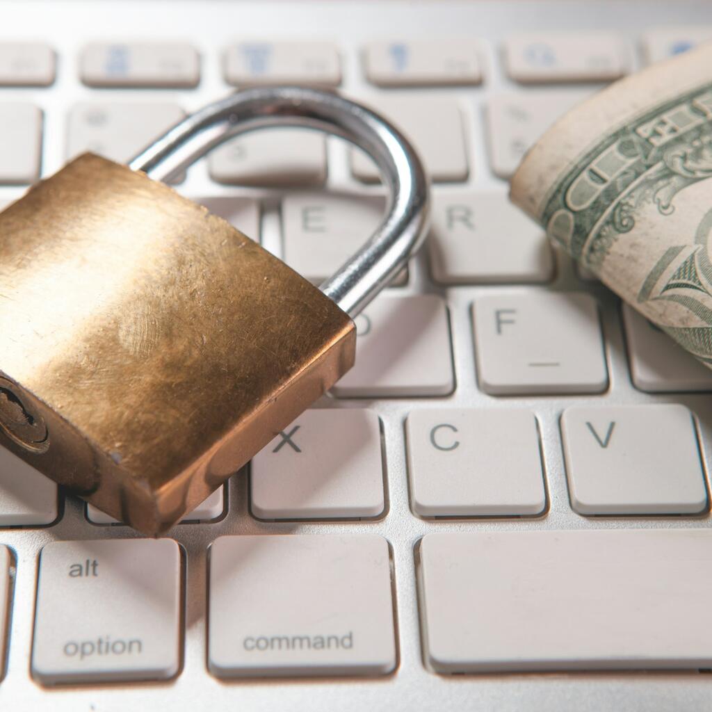 Padlock and dollar bill on keyboard representing currency payment barriers